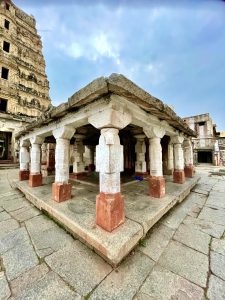 A stone pavilion with a series of rectangular columns, leading to a large gopura (tower) of Durga temple, near the famous Virupaksha Temple, Hampi, Karnataka. 