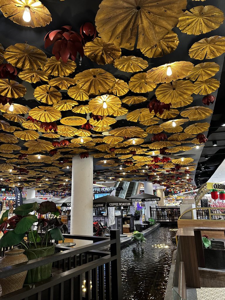 Flower-shaped lights shine down on a water feature inside a shopping center