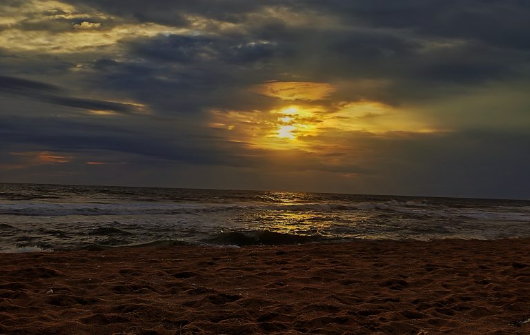 Sunset beach seascape vista. The light reflecting on the sea as the waves rolling toward the sand.