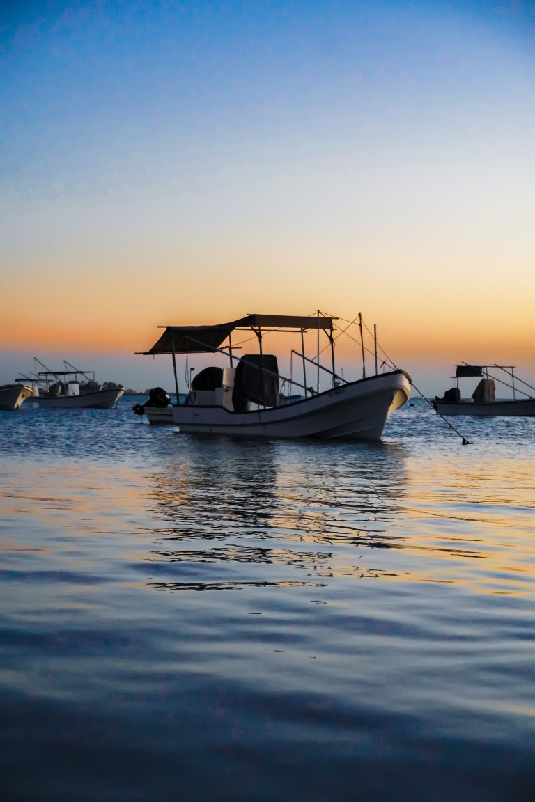 Malkiya Beach, Bahrain: A tranquil seaside scene with a small boat gently resting on the shore, framed by the golden hues of the setting sun. Serenity meets simplicity in this coastal snapshot.