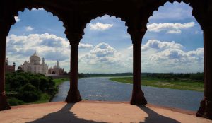 Side view of Taj Mahal with three doors, overlooking Yamuna River under a beautiful sky.