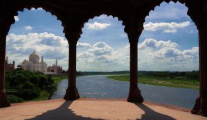  Side view of Taj Mahal with three doors, overlooking Yamuna River under a beautiful sky.
