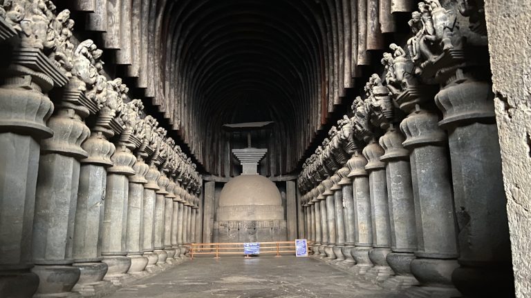 Old cave carved ornately with a hall of columns and a dome at the end