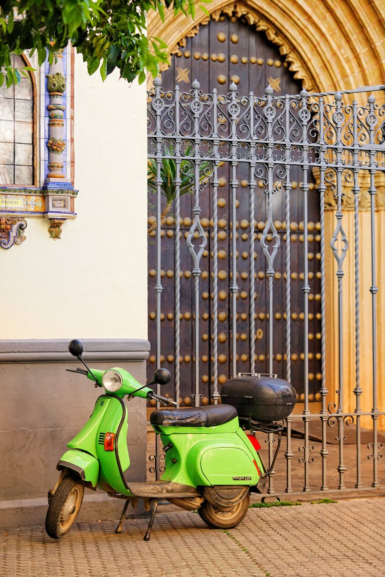 Green scooter parked in front of a romanic church