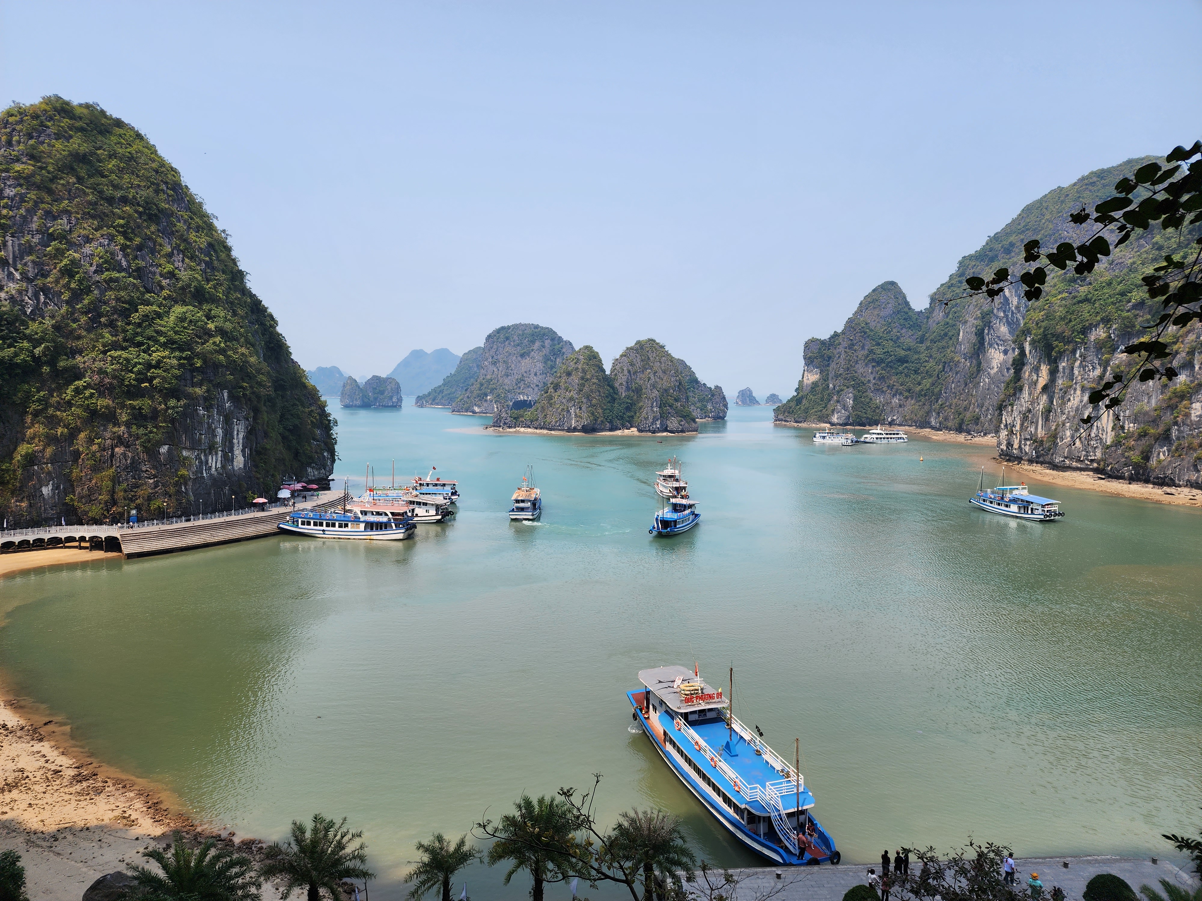 Boats on Ha Long Bay surrounded by rocky cliffs