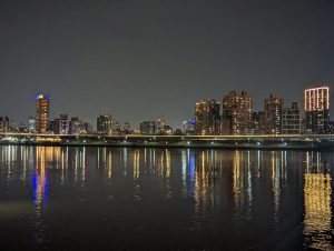 View of Taipei from the port at night, with reflection of the river in the forefront.