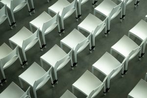 Rows of white plastic chairs on a concrete floor, seen from above
