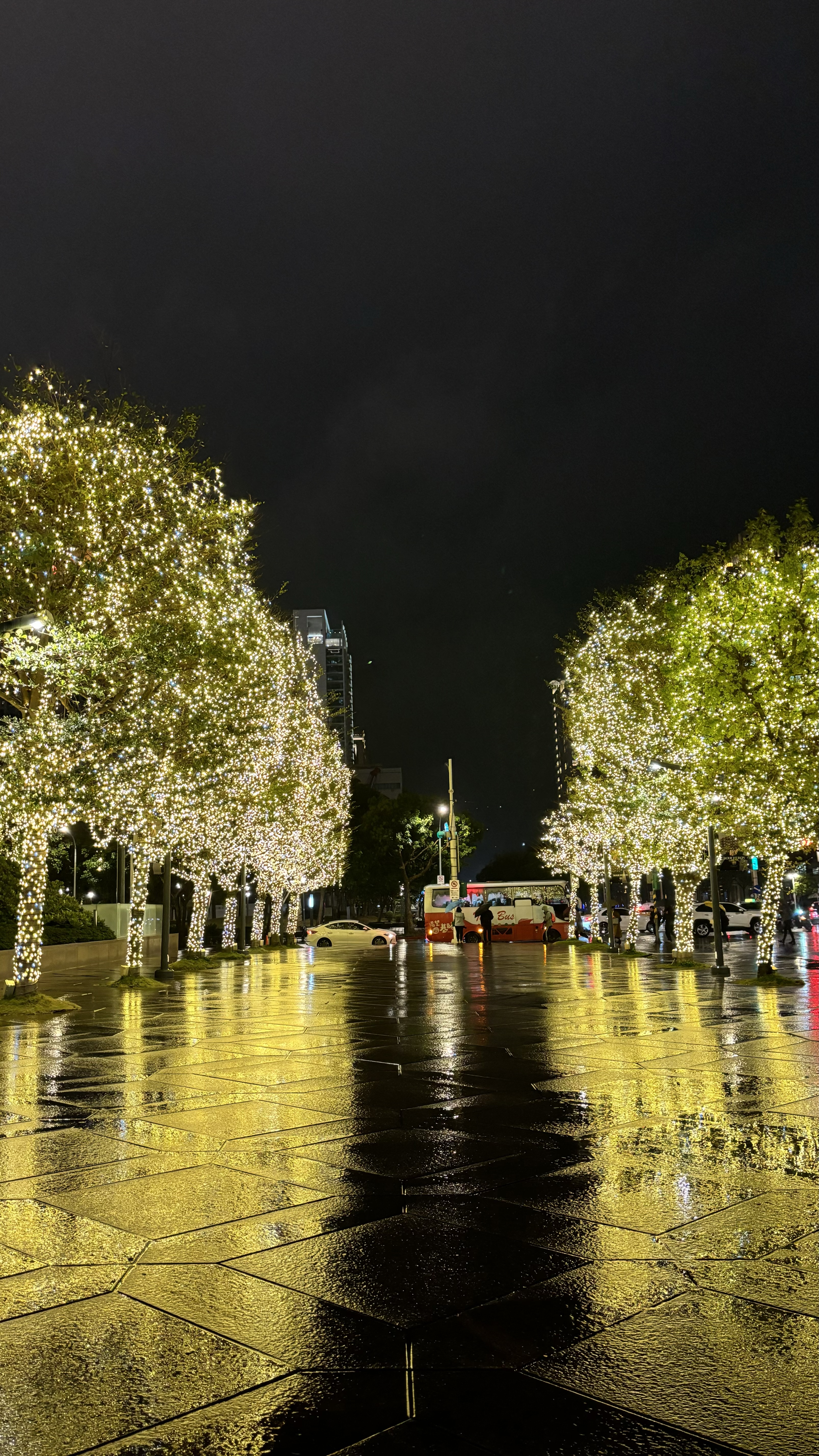 Night before WordCamp Asia 2024 outside Taipei 101, with lighted trees and a bus