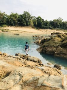  a boy is walking beside blue river photography
