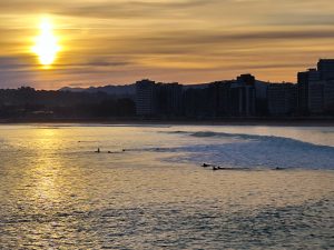 sunset on San Lorenzo beach, surfers in the water paddling (Gijón, Asturias, Sapin)
