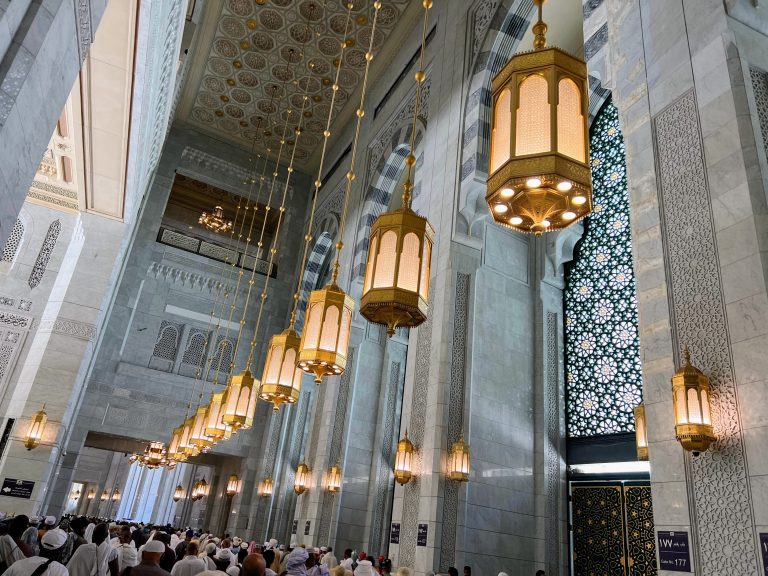 Ceiling chandelier hanging over worshipers in a mosque.