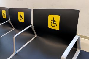 Black chairs with yellow reserved seating stickers at an airport's waiting room.