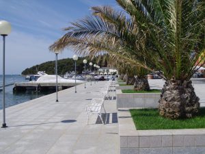 Palm trees, benches and lamp posts on a footpath near the beach