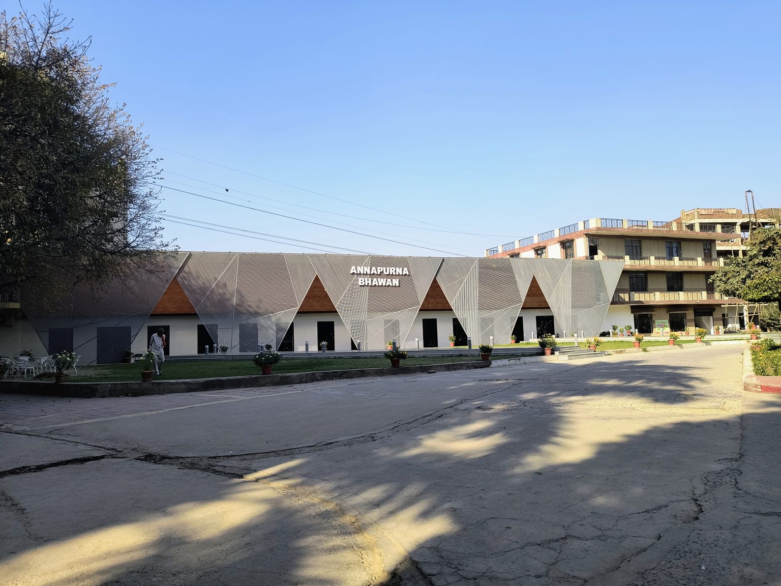 Annapoorna Bhawan: Student kitchen and dining area with seating, adjacent to parking lot and tree.