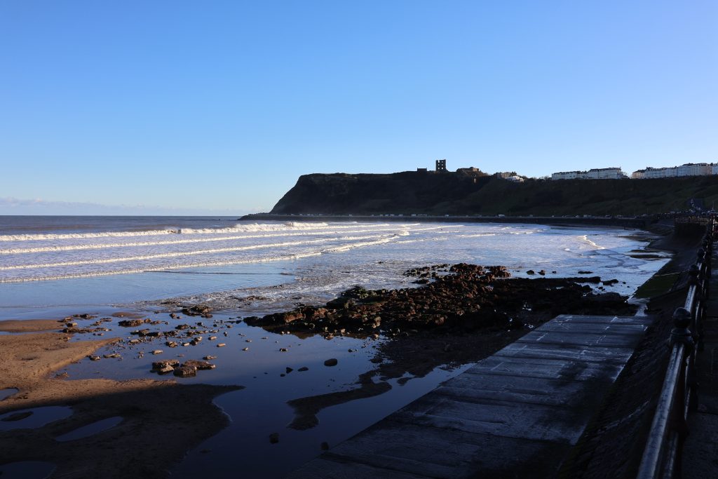 Scarborough Castle with a calm sea in the foreground.