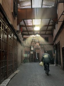 View larger photo: small alleyway with a man on a bicycle and sunrays 