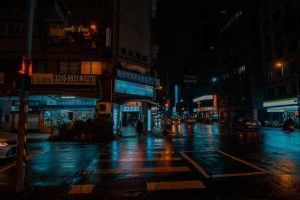 A busy city street at night with vibrant neon signage illuminating the scene under a rainy ambiance, as vehicles and pedestrians navigate the wet roads. Taipei, Taiwan.
