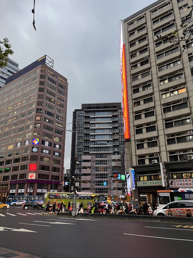 Photographing a busy street in a big city with tall buildings and many cars and pedestrians crossing the street.