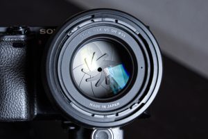 Closeup of a black digital camera showing the closed diaphragm blades of a big aperture lens