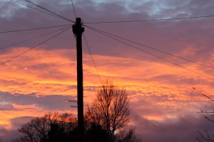 Sunset with a lamppost with wires stretching into the distance.