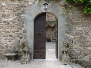 Doorway entrance to Castello di Vincigliata, Fiesole in Florence Italy. One door is open revealing the courtyard. The door is guarded by two stone lions