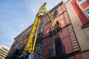 View larger photo: Huge concrete pump with a yellow arm pumping into a building