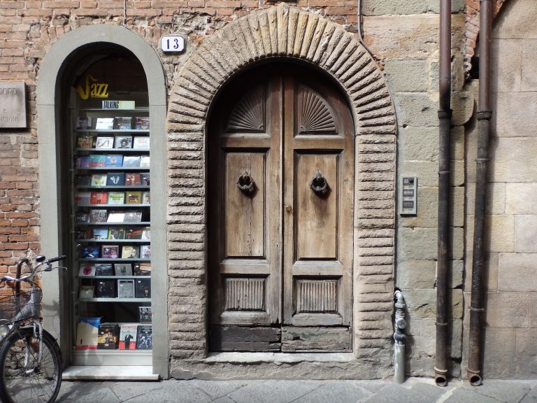 Wooden arched door by the side of a music shop window taken in Florence, Tuscany, Italy.