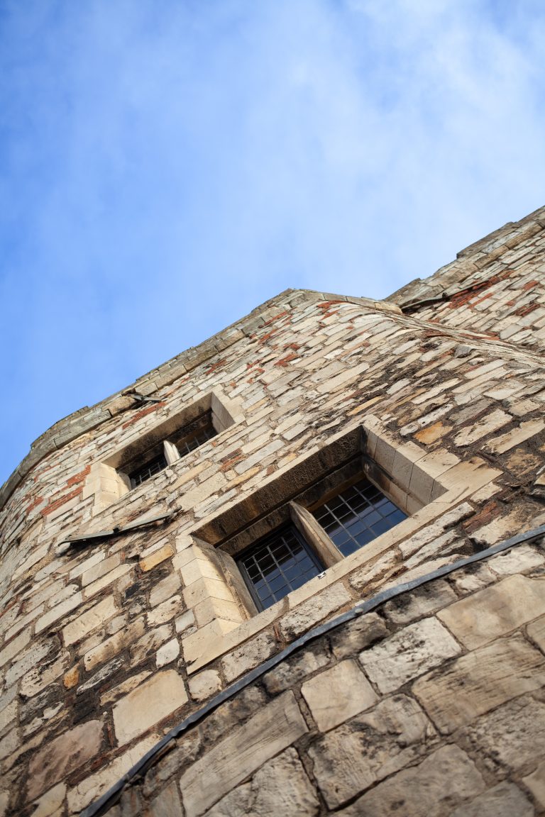 Looking up at an old building with a couple of windows and a blue sky