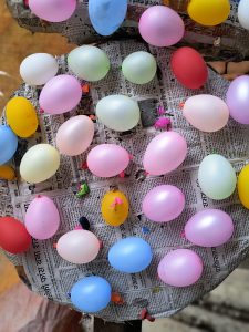 Balloons arranged for target practice. Colorful balloons on newspaper-covered surface.