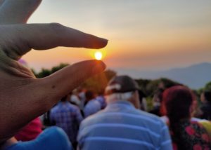 Nature's jewel: capturing the setting sun between two fingers, resembling the grasp of a pearl