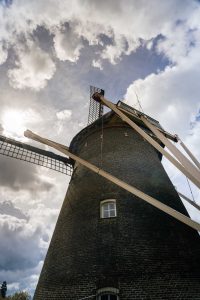 An up close photograph of a typicall Dutch mill. Shot upwards with a blue sky in the background.
