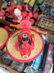 A close-up of a red toy helicopter with a wooden base, surrounded by various other colorful toys.