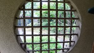 View of a park from a round window with a bamboo lattice