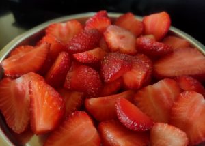 A bowl full of freshly sliced ripe strawberries.