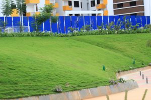 Green lawn in front of an apartment complex with a tall fence