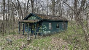 Run down abandoned green wood cabin covered in graffiti in the woods (YMCA Camp Benson, Mt. Carroll, IL)