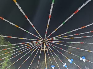 Colorful strings radiate outwards like spokes from the center of a wheel, creating a vibrant and festive atmosphere against the backdrop of the night sky.