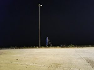A deserted toll tax area at night with a solitary lamppost and a starry sky overhead.