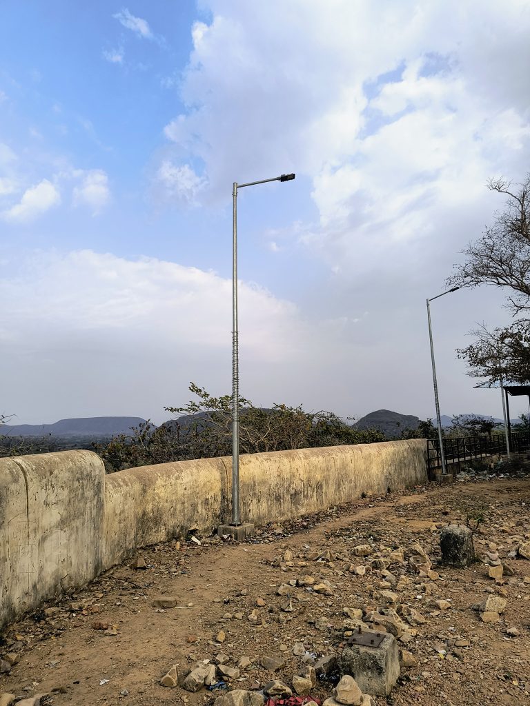 Two streetlights against a cloudy sky, overlooking a rocky terrain with scattered debris.