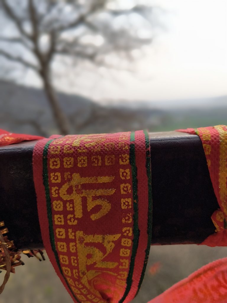 Close-up of a sacred cloth with colorful patterns and symbols, against a blurred background.