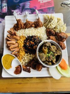 A white plate full of different varieties of non-veg items including salad and some pickles.
