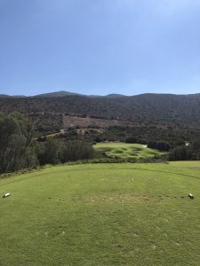 View larger photo: A golf course with a clear blue sky and hula in the background.