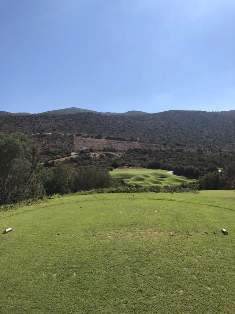 A golf course with a clear blue sky and hula in the background.