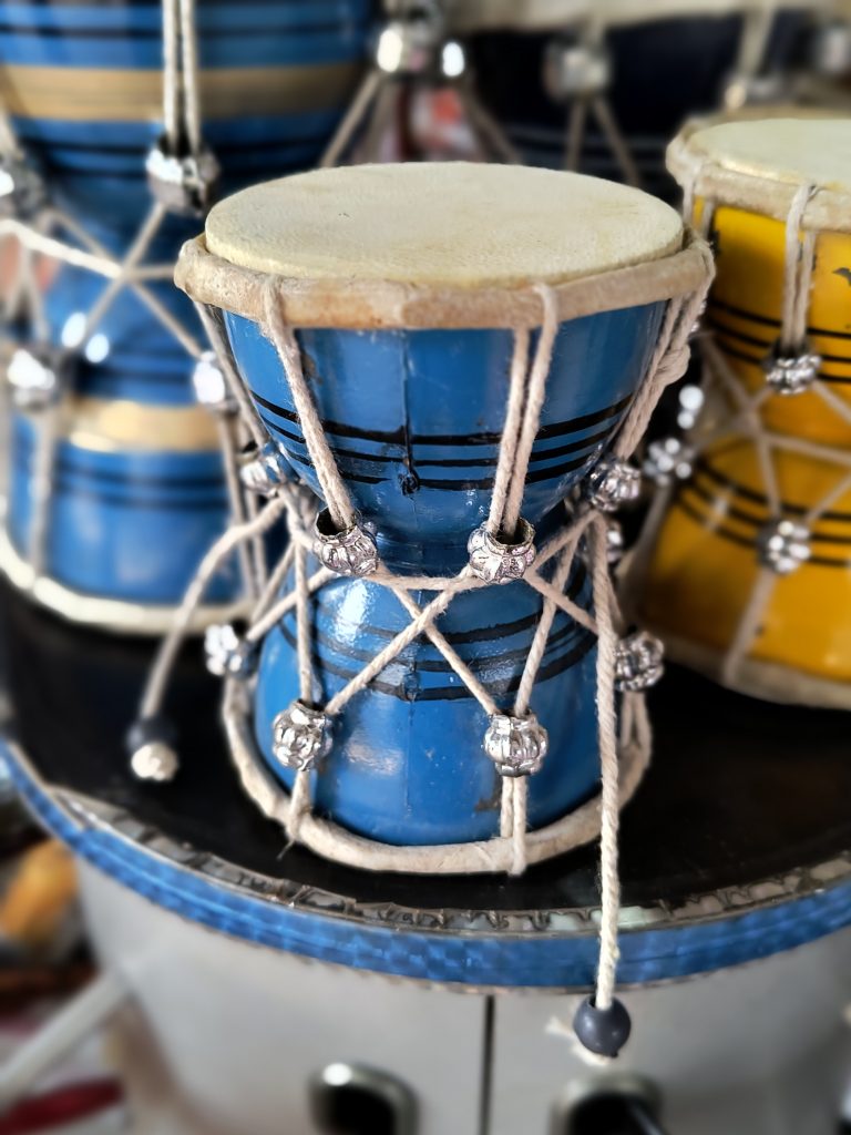 Close-up of a blue and yellow “Shiv Damaru”, a traditional instrument associated with Lord Shiva in Hindu mythology.