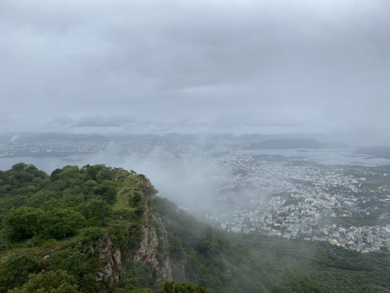 City and a lake partly hidden by a lot of mist, with greenery in the front