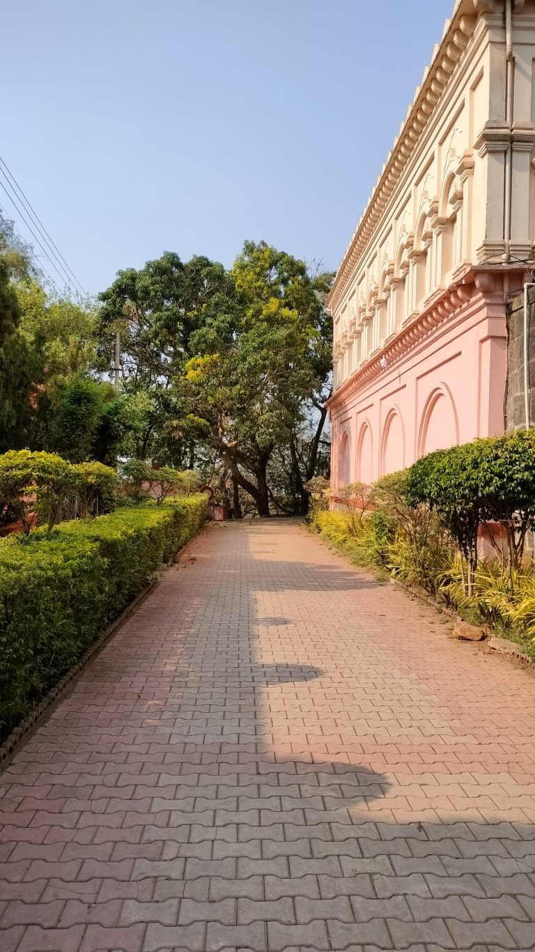 Footpath behind palace wall decorated with trees one side