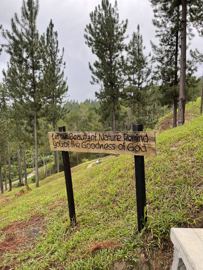 sloppy greeny mountain with a lot of pine trees. There’s a saying carved in a wood that says “Let the Beauty of Nature Remind you of the Goodness of God”.