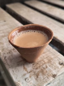 Close-up of a traditional clay cup filled with tea, placed on a wooden surface.