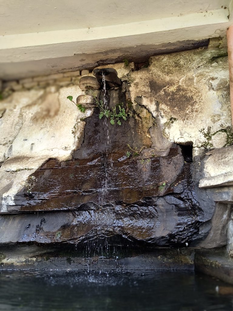 Water flowing from a spout into a pool at Hanuman Dhara, a Hindu religious site in Chitrakoot, creating a serene and tranquil atmosphere.