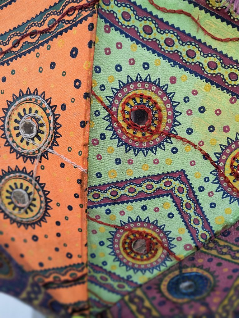 Colorful, embroidered fabric with intricate patterns and vibrant hues, originating from South Asian cultures.